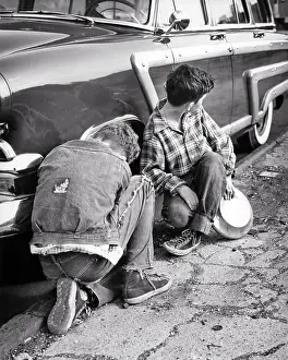 Larceny: Two Boys in Ragged Clothes Stealing Hubcaps from