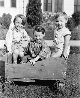 Naive: Three boys sitting in a push cart and smiling