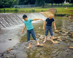 Two Boys Wading Barefoot in Rocky Stream Just