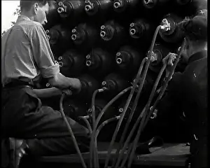 Cannisters: Two British Men By a Large Stack of Gas Cannisters