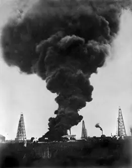 Gusher: A burning gusher, smoke above a burning ?