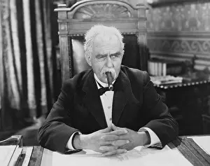 Skeptic: Businessman smoking cigar at desk