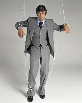 Helpless: Businessman Suspended on Puppet Strings Looking at Camera