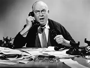 Stress: Businessman using multiple phones