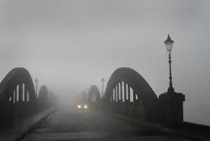 Headlights: A car in thick fog on the concrete bridge over the River Dee