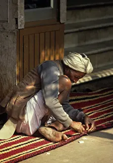 Stitching: Carpet maker stitches the hem of a striped carpet, Rajasthan