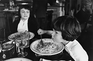 Bolognese: A child eats spaghetti in a restaurant