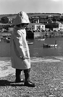 Souwester: Child in sou?wester hat and coat by a harbour