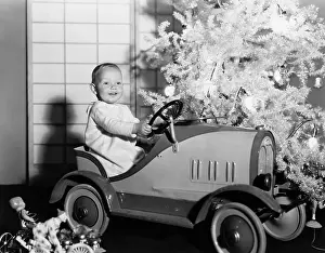 Celebratory: Child with toy car under Christmas tree