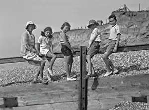Pebbly: Five children on a breakwater at the seaside