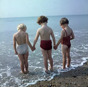 Pebble: Three children holding hands, paddling in the sea