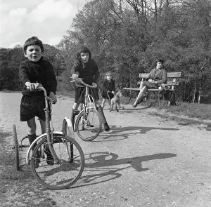 Trike: Three children and their mother in a park