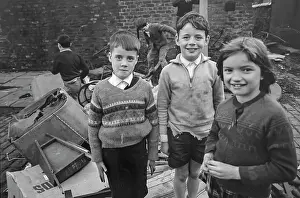 Heap: Three children with others behind playing on rubbish heap