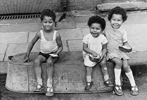 Upturned: Three children sitting on an upturned tin bath