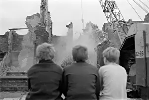 Three children watching housing demolition