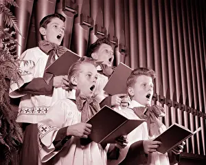 Choirboys: Four Choirboys Singing Together Holding Hymn Books