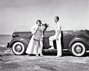 Whitewall: Classy Couple Standing by Convertible Car on Beach