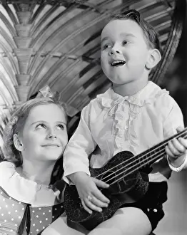 Sibling: Close-up of a boy playing a guitar with his sister