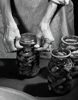 Cucumbers: Close-up of elderly woman's hands sealing lid