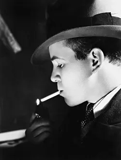 Close Ups: Close-up of a young man with a hat lighting a cigarette