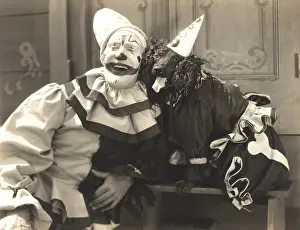 1910s 1940s: Clown posing with dog dressed in clown costume