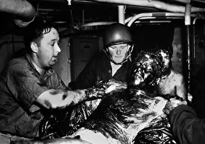 Scrape: Coast Guardsmen scrape a thick coating of oil