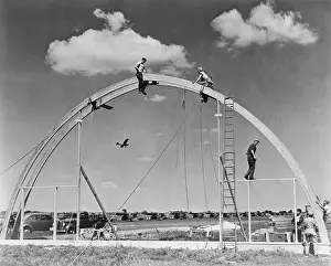 Laminated: Construction workers on airplane hangar with prefabricated