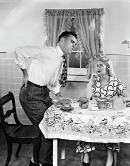 Backache: Couple at Breakfast Table Man with Hand on Hip Suffering B