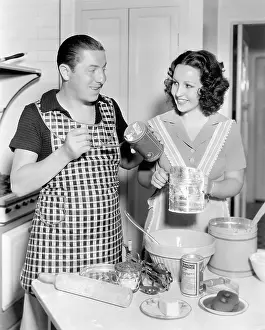 Cooperate: Couple together in the kitchen baking a cake
