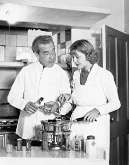 Cooperate: Couple together in the kitchen preparing a fondue