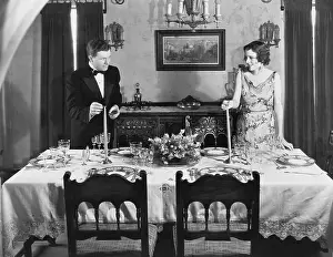 Collaborate: Couple lighting candles on table set for dinner