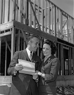 Nicely: Couple looking at paperwork in front of their new house