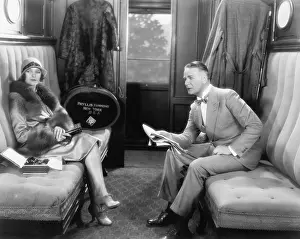 Hatbox: Couple sitting together in a compartment of a train