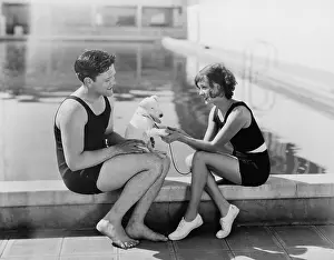 Flirtatious: Couple sitting with their puppy next to a pool