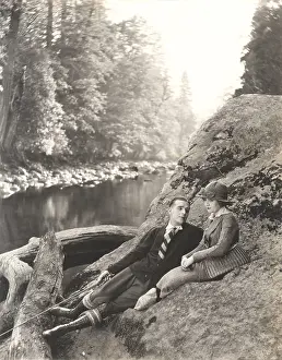 Wooing: Couple sitting on rock beside stream