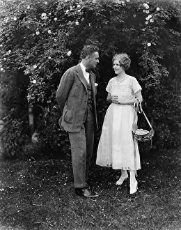 Coquettish: Couple standing together in a yard looking at each other