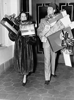 Reverie: Couple walking and holding stacks of presents