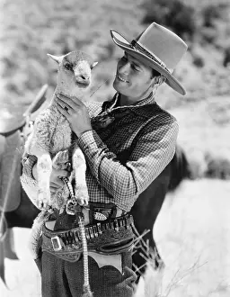 Three Quarter: Cowboy carrying a lamb and smiling