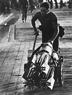 Purpose: A crewman wheels heavy bombs across the flight