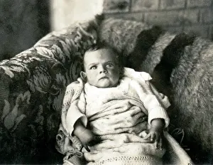 Sepia Images: Cross looking baby on a sofa