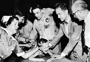 Inoculations: Several doctors and nurses restrain young ?