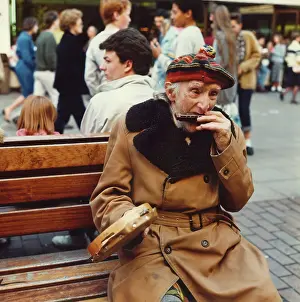 Harmonica: Elderly man playing music on a bench