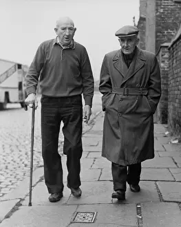Raincoat: Two elderly men walking along a pavement