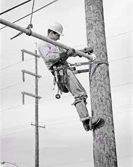 Lineman: Electric Lineman on Utility Pole Secured with Safety Belt