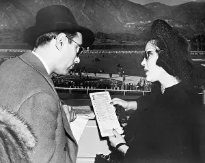 Inquire: Elegant couple at a horse race looking at a program