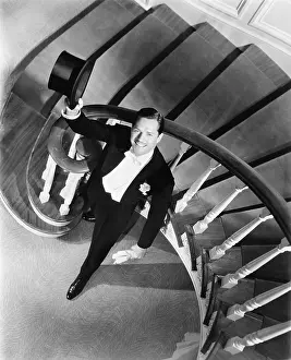 Formalwear: Elegant man looking up from the bottom of a staircase