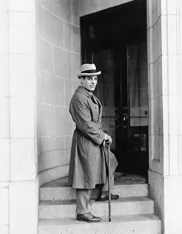 Fedora: Elegantly dressed man standing in a door way of an office
