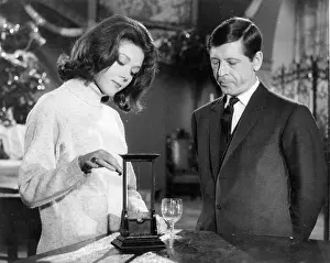 Protagonist: Emma Peel discussing a model guillotine with a protagonist