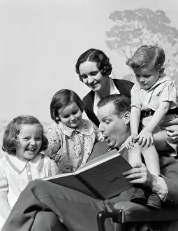 Storytelling: Family of five grouped around father reading