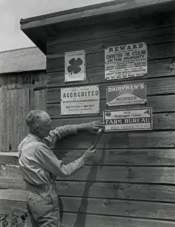 Attaches: Farmer attaches another membership sign to his